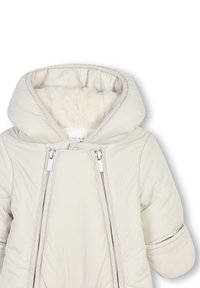 Manteau en duvet beige avec une capuche doublée de fourrure, une fermeture éclair à l'avant et des poignets côtelés. Extérieur lisse avec une texture douce.