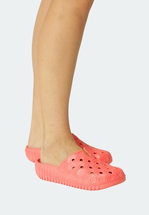 Coral rubber clogs with cut-out wave patterns and textured soles, designed for slip-on use. Rounded shape and open back for breathability.