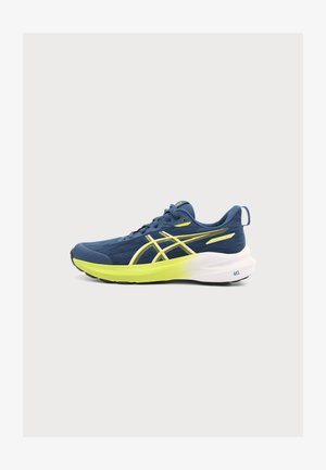 Zapatilla de correr azul y amarilla con suela blanca, parte superior de malla y logo de Asics en el lateral vista desde el exterior.