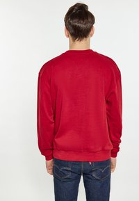 Felpa rossa con maniche lunghe, colletto rotondo e polsini a coste. Realizzata in tessuto morbido, presenta una texture liscia e una vestibilità comoda.