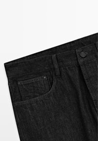 Pantaloni in denim nero con tasca anteriore, chiusura a bottoni e superficie leggermente testurizzata. La cintura è cucita con una finitura pulita.