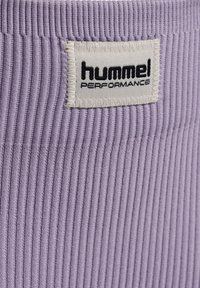 Lavendel geribde stof met prominente textuur, voorzien van een wit label met zwarte tekst "hummel PERFORMANCE." Eenvoudig, schoon ontwerp.