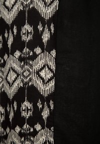 Tessuto a contrasto bianco e nero con motivi geometrici e linee, con una sezione solida nera a destra. Superficie testurizzata.