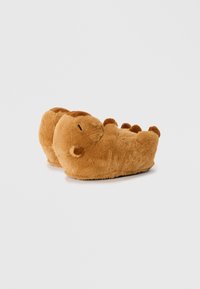 Bruna plyschtofflor formade som en dinosaurie, med en mjuk textur, rund kropp, tydliga tår och en ansiktsdetalj med svarta ögon.