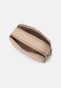 Beige läderväska med dubbla dragkedjefack. Slät textur, rektangulär form och en minimalistisk design. Diskret logotypdetalj inuti.