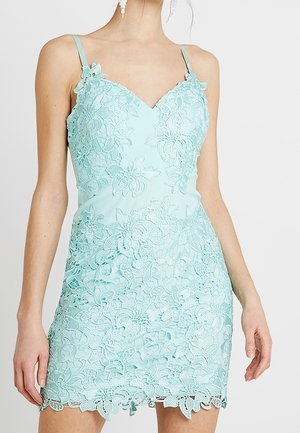 Jasnoniebieska sukienka bez rękawów z koronki z kwiatowymi wzorami i cienkimi ramiączkami, noszona przez osobę widoczną od szyi do połowy uda.