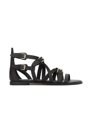 Sandale gladiator negre din piele netedă, cu multiple barete și catarame aurii. Talpă plată și design decupat în vârf.