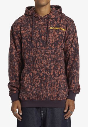 Sudadera con capucha en un oscuro color granate con un gráfico de multitudes en rojo y naranja. Presenta un bolsillo tipo canguro y un logo amarillo en el pecho.