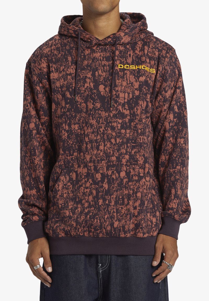 Sudadera con capucha en un oscuro color granate con un gráfico de multitudes en rojo y naranja. Presenta un bolsillo tipo canguro y un logo amarillo en el pecho.