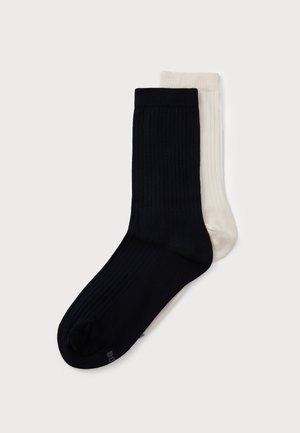 Socken aus Baumwollmix in Marineblau und Creme. Gerippte Textur, knöchelhoch. Sichtbare Zehnähte und kontrastierende Farben. Geeignet für die Freizeit.