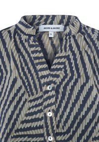 Blouse à motifs avec un décolleté en V, fermeture à boutons sur le devant et un design à rayures verticales en bleu marine et beige. Tissu texturé avec un éclat subtil.