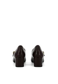 Scarpe con tacco in pelle lucida marrone, con punta arrotondata e dettaglio a fiocco decorativo sul lato. Il design del tacco spesso offre stabilità.