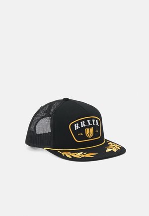 Casquette trucker noire en mesh avec des feuilles jaunes brodées sur la visière et un patch logo B.R.X.T.N. sur le panneau avant.