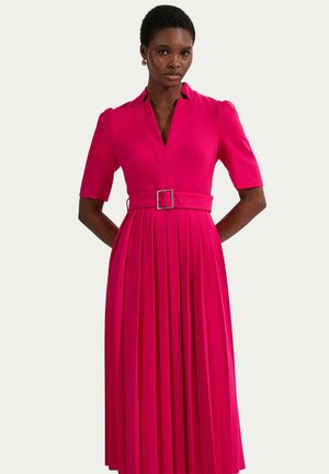 Donna che indossa un abito midi plissettato rosa acceso con maniche corte, collo a V e cintura abbinata con fibbia quadrata.