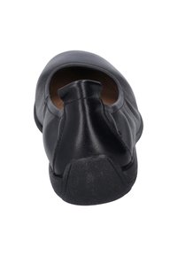 Zapato negro tipo slip-on con puntera redondeada, parte superior de cuero liso, detalle de elástico en la parte trasera y suela de goma texturizada.