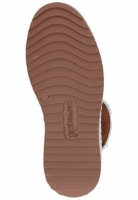 Brązowa gumowa podeszwa z teksturowanymi falistymi wzorami, z wytłoczonym logo. Przedstawia projekt obuwia wsuwanego dla komfortu i stabilności.