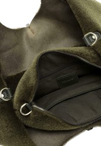 Sac vert olive avec un extérieur doux et texturé et un intérieur lisse. Comprend une poche zippée et des accents en métal.