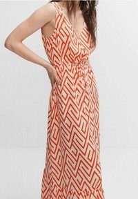 Robe maxi avec décolleté en V, sans manches, dans un motif zigzag orange et crème, avec une taille élastique et un ourlet volanté.