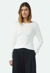 Witte langemouwtrui met een ronde halslijn en geribde manchetten, in een relaxte pasvorm en een gladde textuur, gecombineerd met zwarte broek.