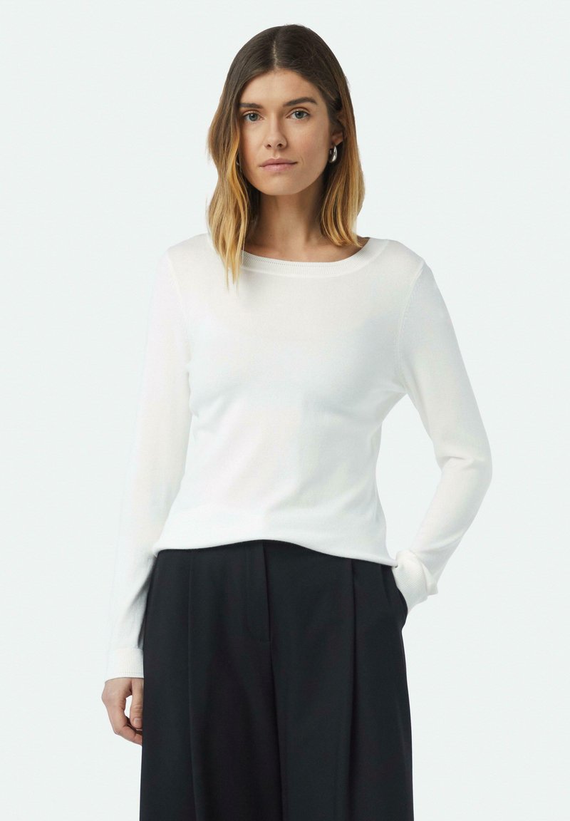 Witte langemouwtrui met een ronde halslijn en geribde manchetten, in een relaxte pasvorm en een gladde textuur, gecombineerd met zwarte broek.