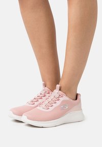 Roze mrežaste atletske cipele s teksturiranom površinom, platnenim vezicama i bijelim podstavljenim đonom. Imaju logo sa strane.