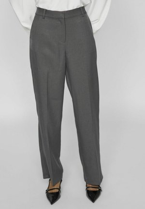 Pantalones grises de corte recto, con una textura suave y bolsillos laterales, combinados con tacones negros puntiagudos.