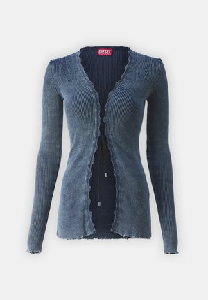 Rebrastan džinseni kardigan v gradientnem modrem odtenku, z ukrivljenim izrezom in sprednjim zapiranjem z nastavljivimi vezalkami ter srebrnimi dodatki.