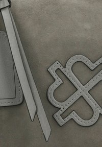 Dettaglio di una borsa in pelle grigia con superficie testurizzata, lunghe tracolle piatte e un accento logo cucito.