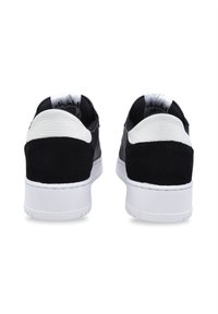 Sneaker in pelle nera e suede con un accentuazione del tallone bianca, materiali testurizzati e una suola in gomma bianca. Presentano un colletto e una linguetta imbottiti.