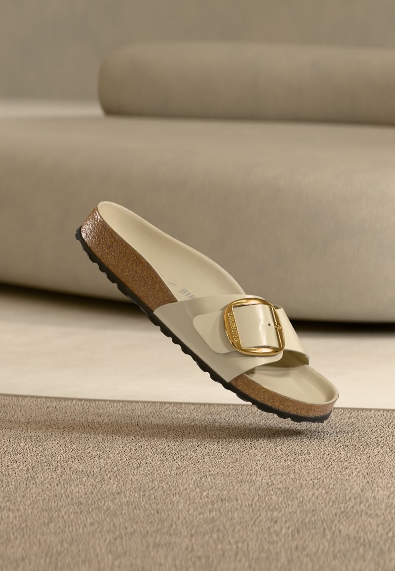 Μπεζ σανδάλι με πλατιά λουρί, μεγάλη χρυσή αγκράφα και υφασμένο φελλό στο πέλμα· μαύρη λαστιχένια σόλα με λεπτομέρειες αντιολισθητικού.