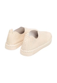 Zapatos de lona color beige claro, con un patrón texturizado similar a reptiles, aberturas elásticas en los laterales y una suela gruesa y estriada.