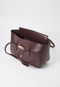 Sac à main en cuir bordeaux avec un design structuré, double anses supérieures, fermeture magnétique et poche intérieure zippée. Texture lisse tout au long.