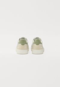 Sneaker verdi e beige con tomaia in pelle liscia, dettagli in camoscio, punta rotonda, collo imbottito e suola in gomma bianca.