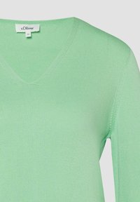 Maglione a maglia verde chiaro con scollo a V e maniche lunghe, con un'etichetta del marchio s.Oliver all'interno del collo.