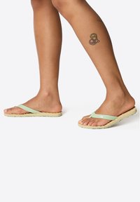 Light green flip flops with a textured, natural cork sole, featuring thin straps and a flexible design.