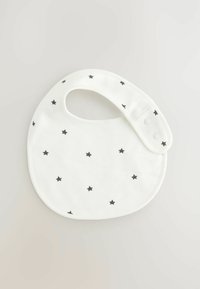 Bavoir en coton blanc de forme arrondie, ornée de motifs d'étoiles noires dispersées et d'une fermeture à pression au niveau du cou. Texture lisse.