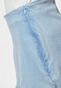 Šviesiai mėlynas džinsinis audinys su lygiu paviršiumi. Yra šoninis užtrauktukas ir kontūrinis dizainas, tinkantis prigludusiai siluetui.