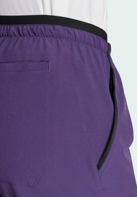 Violette sportieve shorts met een elastische zwarte tailleband, voorzien van een zijzak met rits en vlakke naden voor een gladde afwerking.