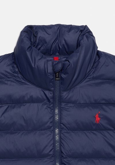 Μπουφάν σε ναυτικό μπλε με ψηλό γιακά, μπροστινό φερμουάρ και μικρό κόκκινο κεντημένο λογότυπο παίκτη πόλο στο στήθος.