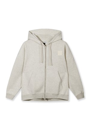 Sudadera con capucha de color gris claro, cierre de cremallera, capucha, bolsillos delanteros, cordones y un pequeño parche cuadrado en el pecho izquierdo, mostrada sobre un fondo blanco.