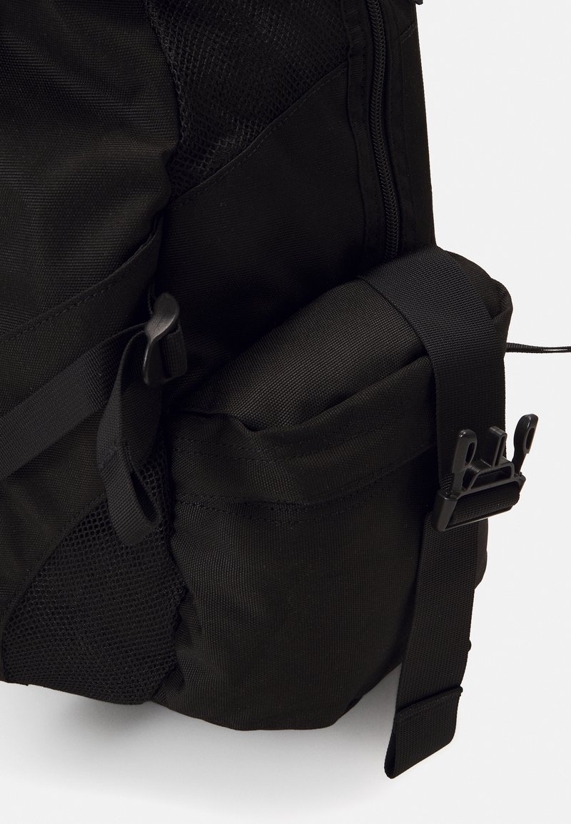 Black backpack featuring a sleek design with mesh and textile materials, side pocket, adjustable strap, and sturdy hardware accents.