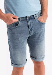 Shorts de mezclilla en lavado azul claro con dobladillos enrollados, cinco bolsillos y cierre con botón. El material parece suave y ligeramente desgastado.