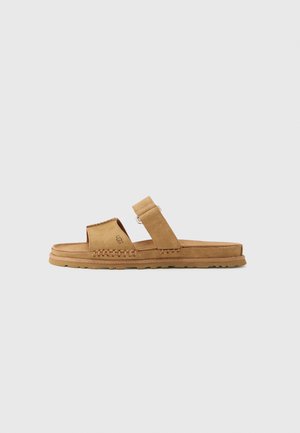 Tan suede slide sandal with two adjustable straps, braided detail along the sole, and a textured rubber outsole for grip.