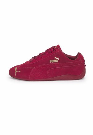 Rood suède sneaker van Puma met een laag profiel, gouden Puma-logo op de zijkant en teen, platte zool en lintachtige veters.