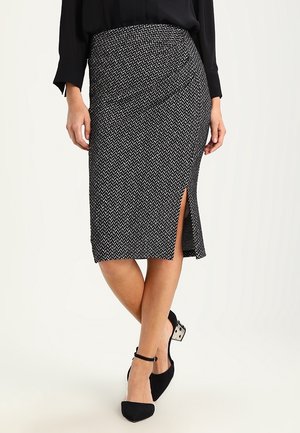 Jupe crayon noire et blanche à motifs, longueur genou, avec une fente sur le côté, fabriquée en tissu texturé, offrant un design ajusté et une taille élastique.