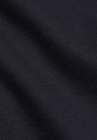 Gros plan sur un tissu texturé bleu marine foncé montrant un tissage fin et de légers plis, mettant en valeur le détail du matériau.