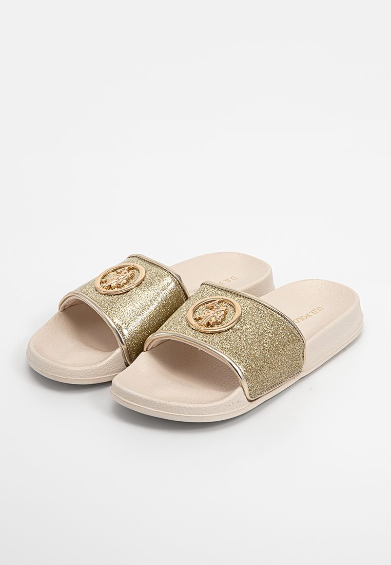 Goldene Glitzersandalen mit einem breiten Riemen und einem runden goldenen Emblem. Weicher beiger Fußbett und Sohle, glatte Textur, minimalistisches Design.