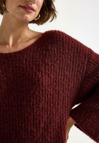 Bordeaux striktrøje med ribbet tekstur, oversized pasform og brede ærmer. Lavet af blødt, fuzzy materiale med bådudskæring.