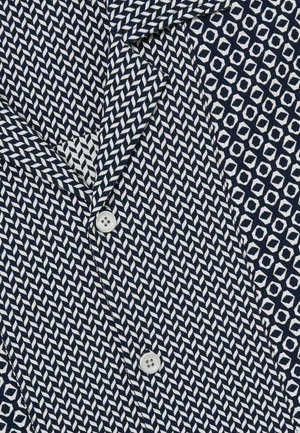 Navy and white patterned shirt featuring a herringbone design with a button closure, and a contrasting geometric pattern on the side.