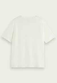 T-shirt bianco a maniche corte disteso, visibile dal retro, su uno sfondo beige chiaro.